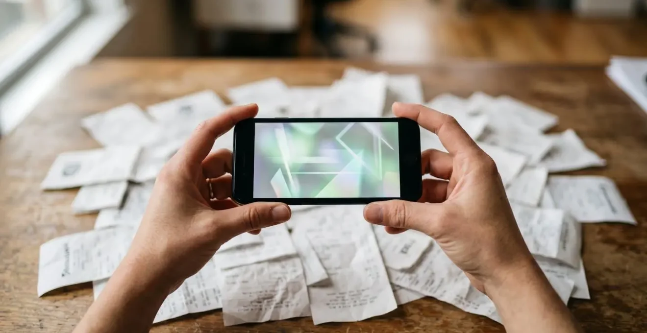 Close-up of hands using mobile device to scan receipts with OCR technology